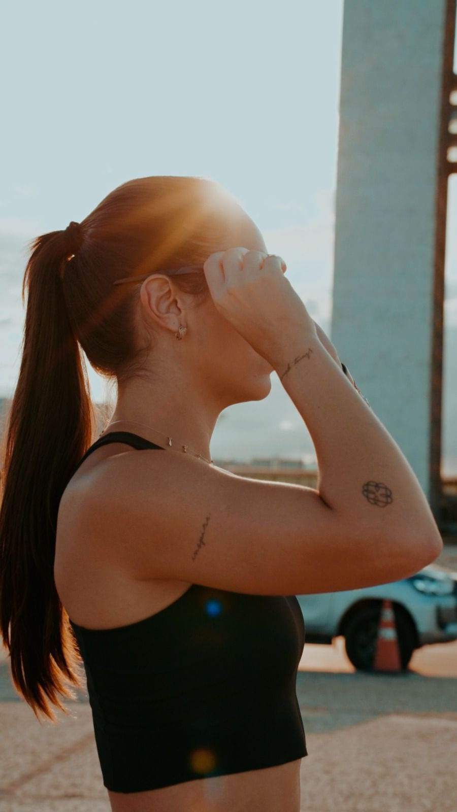 Perfil de Cristina com a mão no cabelo, em contraluz dourado de fim de tarde